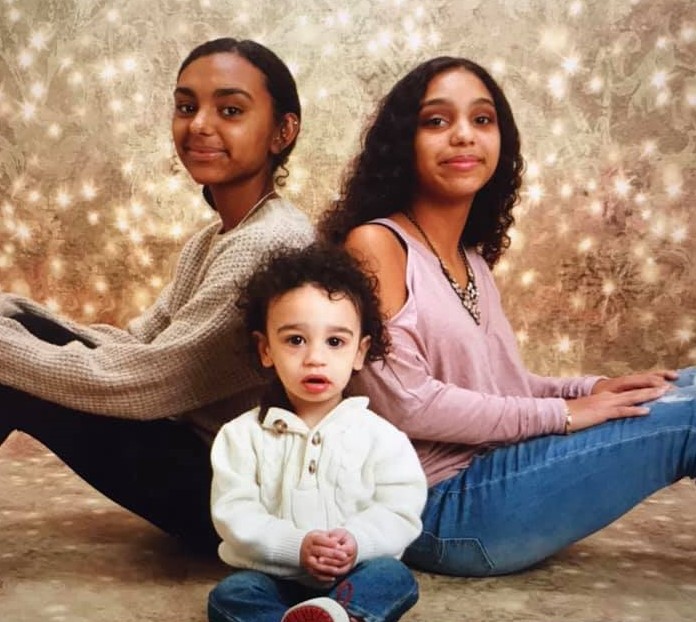 Two teenage girls and toddler boy seated for photo