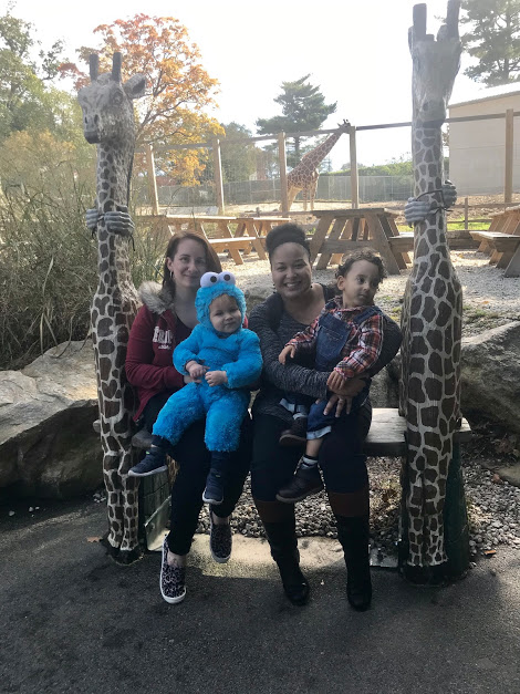 Two mothers pose with children in costume for Halloween at Zoo's giraffe exhibit
